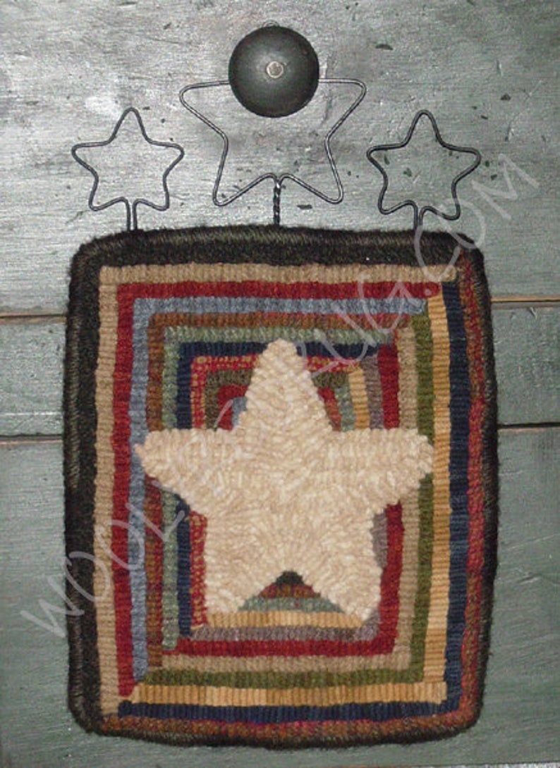 May include: A rustic, square wall hanging with a cream-colored star in the center, surrounded by concentric squares of red, blue, green, and brown. Above the hanging are three metal star cutouts and a small, dark bell.