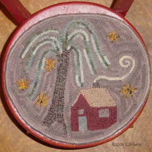 Peut inclure: Un tapis rond cousu à la main avec une bordure rouge. Le tapis représente un arbre, une maison et des formes d'étoiles dans des tons de vert, marron, rouge et jaune. Le tapis est sur une surface en bois.