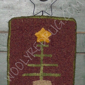 May include: A rectangular, hand-stitched rug with a Christmas tree design. The rug features a brown background with a green border. The tree is yellow and green, with a beige pot. A metal star and ball are attached at the top.