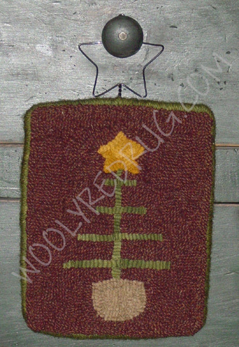 May include: A rectangular, hand-stitched rug with a Christmas tree design. The rug features a brown background with a green border. The tree is yellow and green, with a beige pot. A metal star and ball are attached at the top.