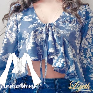 Puede incluir: Una blusa de estampado floral azul y blanco con un lazo en el cuello y mangas acampanadas. La blusa es corta y tiene un dobladillo con volantes. El patrón recuerda a un diseño floral vintage. La blusa se muestra en una modelo que lleva jeans azules. El texto "Amelia Blouse" es visible en la imagen.