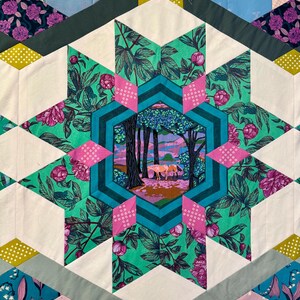 May include: A colorful quilt with a starburst design. The quilt features a central hexagon with a forest scene, surrounded by floral and geometric patterns in shades of pink, green, teal, and white. The quilt is made of various fabric pieces.