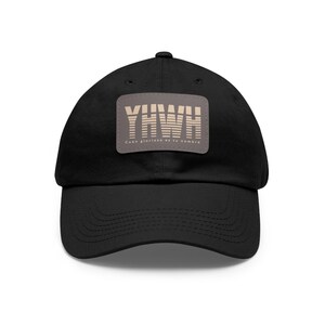 May include: Black baseball cap with a brown patch featuring the word "YHWH" in white with a striped design and the text "Cuan glorioso es tu nombre" in smaller white text.