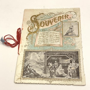 May include: A vintage souvenir card with religious imagery. The card displays illustrations of biblical scenes, including the Nativity and an angel. The word "SOUVENIR" is in gold lettering. The card is tied with a red and blue string.