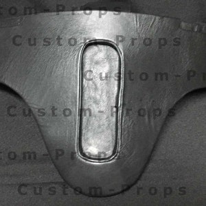 May include: Black leather costume piece with a large oval cutout in the center. The piece is shaped like a belt with a pointed bottom.