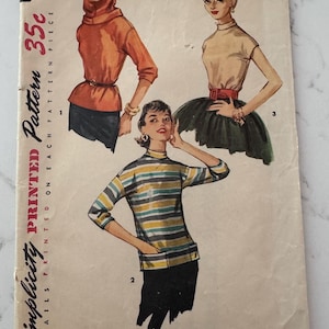 May include: Vintage Simplicity sewing pattern 1227. The cover features illustrations of three different outfits: a hooded top, a short-sleeved top with a skirt, and a striped long-sleeved shirt. The pattern includes the text "Simple to Make."