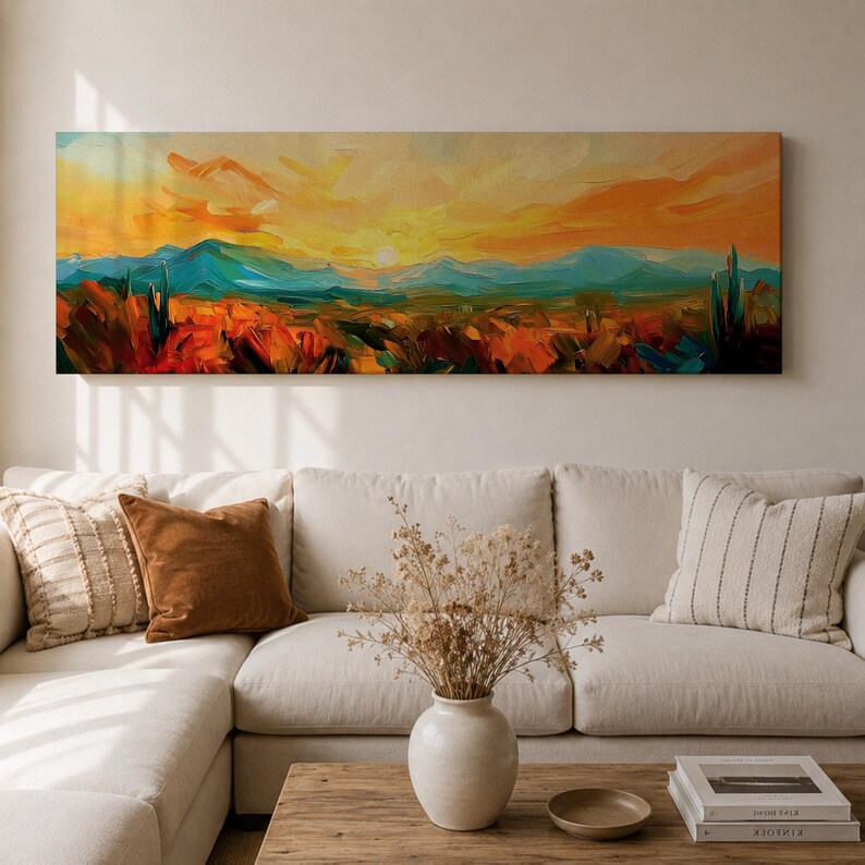 Panoramic desert sunset painting showing distant layered mountains beneath a glowing sun with sweeping orange and gold skies. Thick textured brushstrokes form desert plants and rocky terrain in the foreground while teal and blue ridges fade into the horizon, creating a wide southwestern landscape composition.