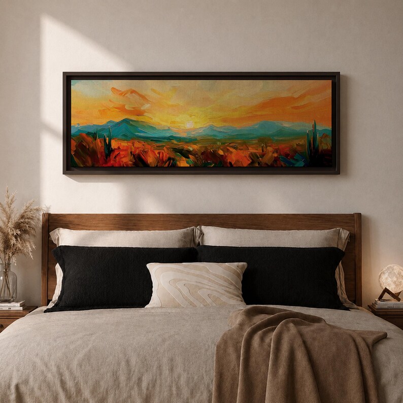 Panoramic desert sunset painting showing distant layered mountains beneath a glowing sun with sweeping orange and gold skies. Thick textured brushstrokes form desert plants and rocky terrain in the foreground while teal and blue ridges fade into the horizon, creating a wide southwestern landscape composition.