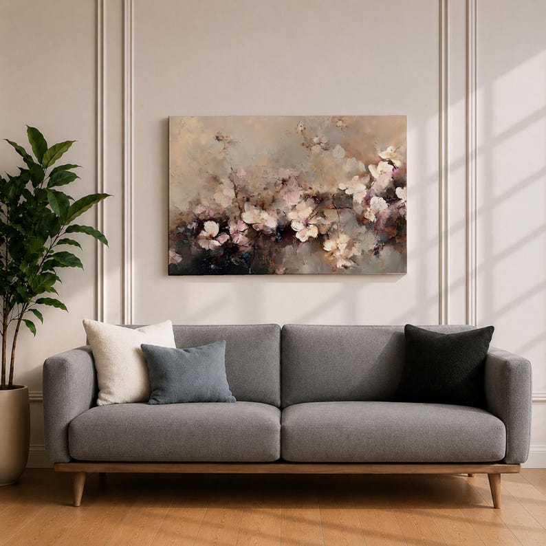 Puede incluir: Un sof&aacute; gris con patas de madera y tres cojines. Una gran pintura floral en tonos apagados de rosa, blanco y marr&oacute;n cuelga sobre el sof&aacute;. Una planta en maceta est&aacute; a la izquierda del sof&aacute;.