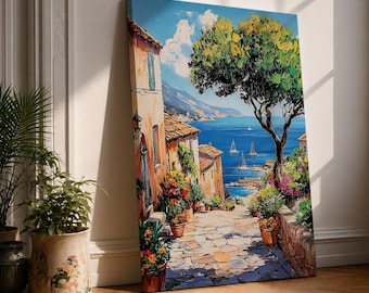 May include: A rectangular canvas print featuring a vibrant oil painting of a Mediterranean coastal village. The scene depicts a stone pathway leading toward a deep blue sea with sailboats, framed by terracotta buildings, potted flowers, and a large tree.
