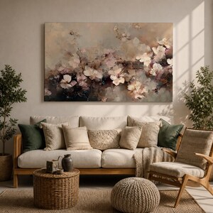 Puede incluir: Una pintura floral abstracta en tonos apagados de beige, marr&oacute;n y rosa cuelga sobre un sof&aacute; crema con varias almohadas. La habitaci&oacute;n est&aacute; decorada con una alfombra tejida, una silla de madera y plantas en macetas, creando un espacio habitable acogedor.