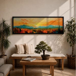 Panoramic desert sunset painting showing distant layered mountains beneath a glowing sun with sweeping orange and gold skies. Thick textured brushstrokes form desert plants and rocky terrain in the foreground while teal and blue ridges fade into the horizon, creating a wide southwestern landscape composition.