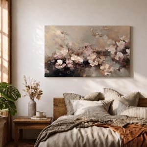 Puede incluir: Pintura floral abstracta en tonos neutros suaves de beige, marr&oacute;n y rosa. La obra presenta un grupo de flores blancas y rosas con acentos oscuros, creando una est&eacute;tica so&ntilde;adora y rom&aacute;ntica. El lienzo es rectangular y cuelga sobre una cama.