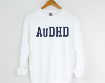 May include: White long-sleeved sweatshirt with the text "AUDHD" printed in navy blue.
