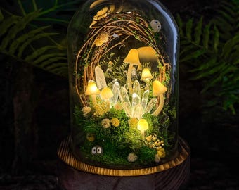 May include: A whimsical terrarium featuring glowing mushrooms, crystals, and moss under a glass dome. The miniature forest scene is illuminated with warm lights, creating a magical ambiance. The dome sits on a wooden base, surrounded by greenery.