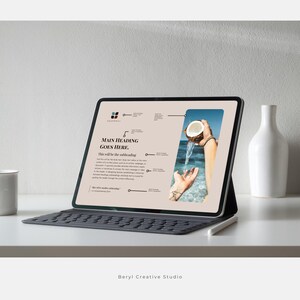 May include: A tablet computer displaying a website with a light brown background and a photo of a hand holding a coconut over a body of water. The text on the website reads "Main Heading Goes Here. This will be the subheading."