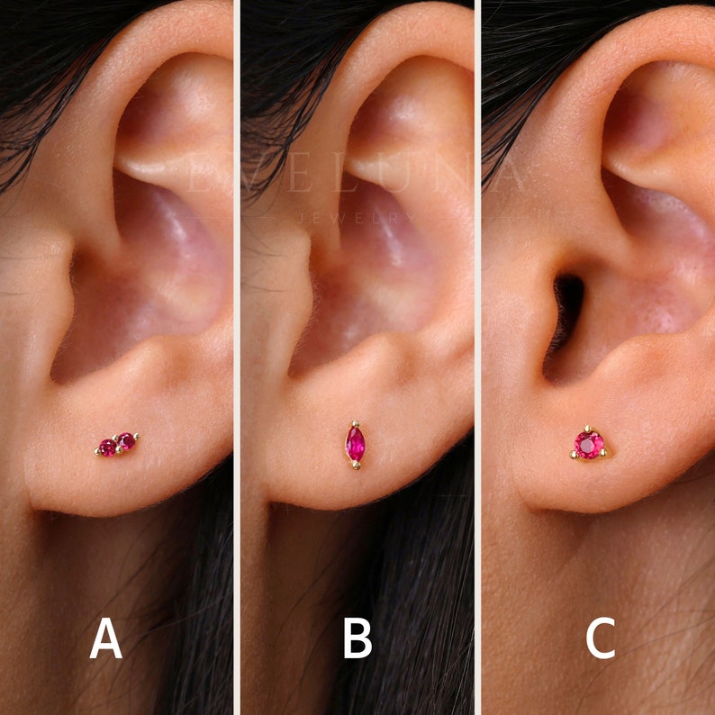 May include: Three close-up images of an ear with different ruby earrings. The first image shows two small round ruby earrings. The second image shows a single ruby earring with a marquise shape. The third image shows a single round ruby earring.