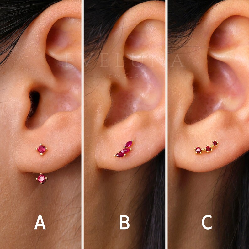 Op de afbeelding: Drie verschillende stijlen robijn oorbellen. Het eerste paar heeft twee kleine robijn studs. Het tweede paar heeft drie robijn stenen in een blaadjesvorm. Het derde paar heeft drie robijn stenen in een gebogen lijn.