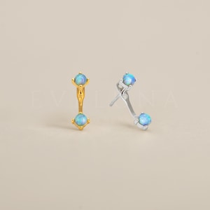 May include: A pair of earrings with a curved bar design. Each earring features two small, round, iridescent blue opal stones.