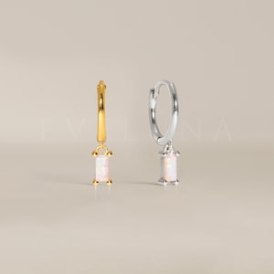 May include: A pair of hoop earrings with a dangling rectangular opal stone. The earrings are available in gold and silver.