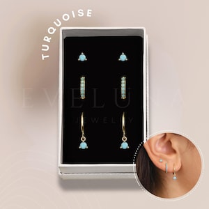 May include: A set of turquoise earrings in a white box. The set includes a pair of small stud earrings, a pair of hoop earrings with turquoise stones, and a pair of dangle earrings with turquoise stones.