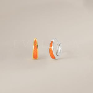 May include: A pair of hoop earrings with a thin band of orange opal set in silver and gold.