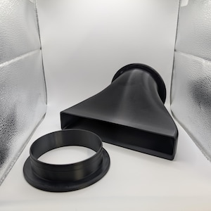 May include: Black plastic funnel with a flared, rectangular opening and a circular base, alongside a separate black ring. The funnel has a smooth, matte finish. The objects are set against a white background.