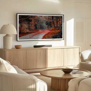 May include: A living room with a light wood cabinet, a couch, a coffee table, and a large framed picture of a fall forest scene on the wall.