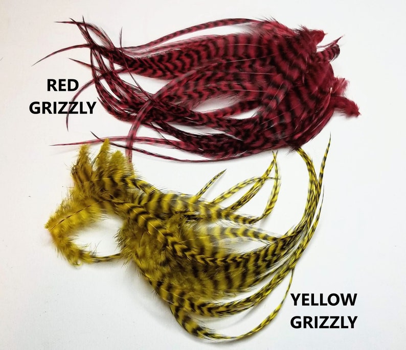 May include: Two bundles of feathers, one red and one yellow, with black stripes. The red bundle is labeled "RED GRIZZLY" and the yellow bundle is labeled "YELLOW GRIZZLY".
