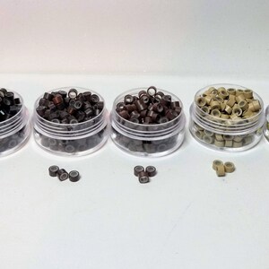 Puede incluir: Cuatro peque&ntilde;os contenedores de microanillos para extensiones de cabello en negro, marr&oacute;n, marr&oacute;n claro y rubio.