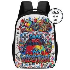 Pode incluir: Mochila preta com um design de grafite colorido com um controle de videogame, um coração pixelado, um joystick e um baú do tesouro. A mochila tem o texto "GAME OVER" e o nome "WESTON".