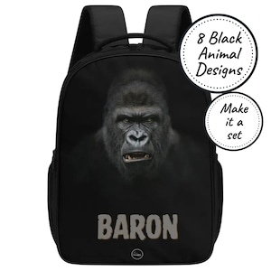 May include: Black backpack featuring a gorilla face with the name "BARON" in large, light-colored letters. The backpack has two shoulder straps and a top handle. A circular graphic reads "8 Black Animal Designs" and "Make it a set."