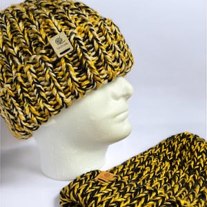 May include: A black and yellow knit beanie and matching neck warmer. Both items have a handmade tag attached.