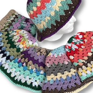 May include: A set of five crocheted hats in various colors, including green, blue, purple, pink, and red. The hats are made with a granny square pattern and have a brown trim.