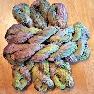 May include: A bundle of multi-colored yarn in shades of green, brown, and purple. The yarn is twisted and knotted together, creating a textured and visually appealing display.