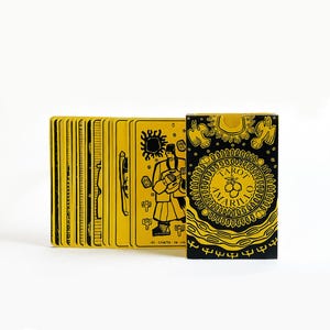Puede incluir: Una baraja de cartas de Tarot Amarillo con un diseño amarillo y negro. La caja presenta una ilustración en negro y amarillo de una persona sosteniendo una copa. El texto "Tarot Amarillo" está impreso en la caja.