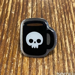 Peut inclure: Épingle en émail noir en forme de tasse à café avec un motif de crâne blanc. La tasse a une bordure argentée et un remplissage de café brun. L'épingle porte le mot "RAPSCALLION" et le site Web "RAPSCALLION.CA".