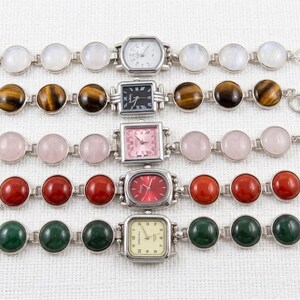 May include: Five silver-toned bracelets with gemstone accents and watch faces. The gemstones include moonstone, tiger's eye, rose quartz, red jasper, and green malachite. The watch faces have various shapes and colors.