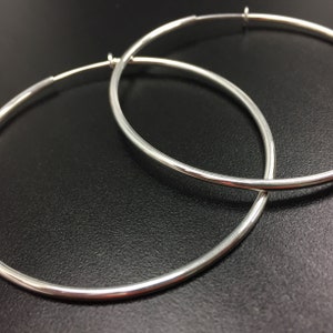 May include: A pair of silver hoop earrings. The hoops are thick and have a smooth, polished finish.