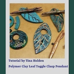 May include: A collection of polymer clay leaf pendants with a toggle clasp. The leaves are in shades of blue and green with gold accents. Some of the leaves have a textured surface. The pendants are on a brown background.