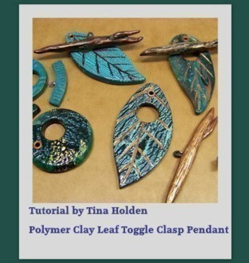 May include: A collection of polymer clay leaf pendants with a toggle clasp. The leaves are in shades of blue and green with gold accents. Some of the leaves have a textured surface. The pendants are on a brown background.