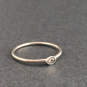 May include: A silver ring with a small evil eye charm. The ring is simple and delicate.