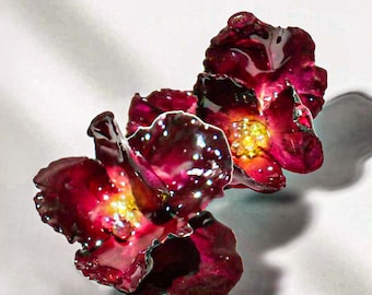 May include: Two dark red glass flowers with a shiny, glossy finish. The flowers have a delicate, intricate design and are arranged in a cluster.