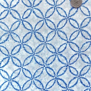 Tessuto di cotone giapponese stampato con tecnica tie-dye Shibori con motivo shippo (cerchi sovrapposti) su sfondo bianco, venduto a mezzo metro.