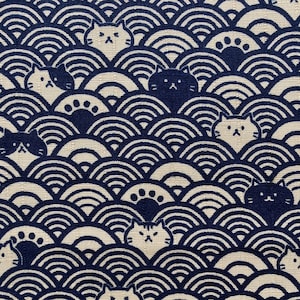 May include: A navy blue and white fabric with a repeating pattern of stylised waves and cat faces. The cats are facing forward with closed eyes and have a simple design.