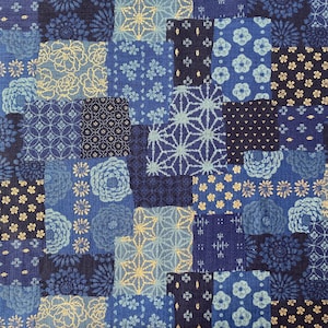 May include: A patchwork fabric in various shades of blue, with floral and geometric patterns. The design includes squares of navy, light blue, and gold, creating a textured textile. The fabric is suitable for various craft projects.