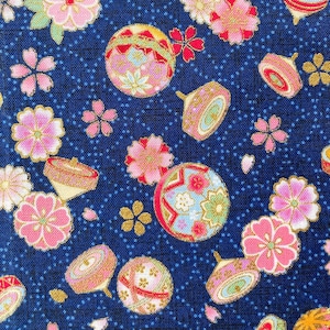 Peut inclure: Un tissu bleu marine avec un motif répété de motifs floraux roses et dorés, de boules décoratives et de toupies. Le motif comprend des fleurs de cerisier et d'autres éléments floraux.