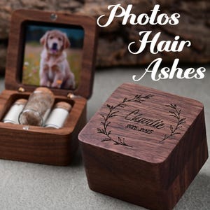 May include: Wooden keepsake box with a photo of a puppy inside. The box is open, revealing small glass vials. The lid of a second box is engraved with the name "Charlie" and the years 2005-2025, surrounded by a laurel wreath. The words "Photos Hair Ashes" are written above.