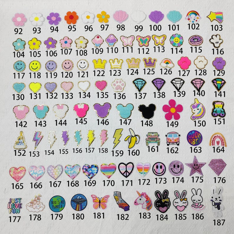 May include: A collection of decorative iron-on patches in various shapes and colors. Designs include flowers, crowns, butterflies, smiley faces, hearts, diamonds, and cartoon characters. Each patch is numbered for easy selection.