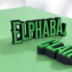 May include: Black and green 3D letters spelling "ELPHABA" with a small green broom next to the last letter. The letters are on a green surface.